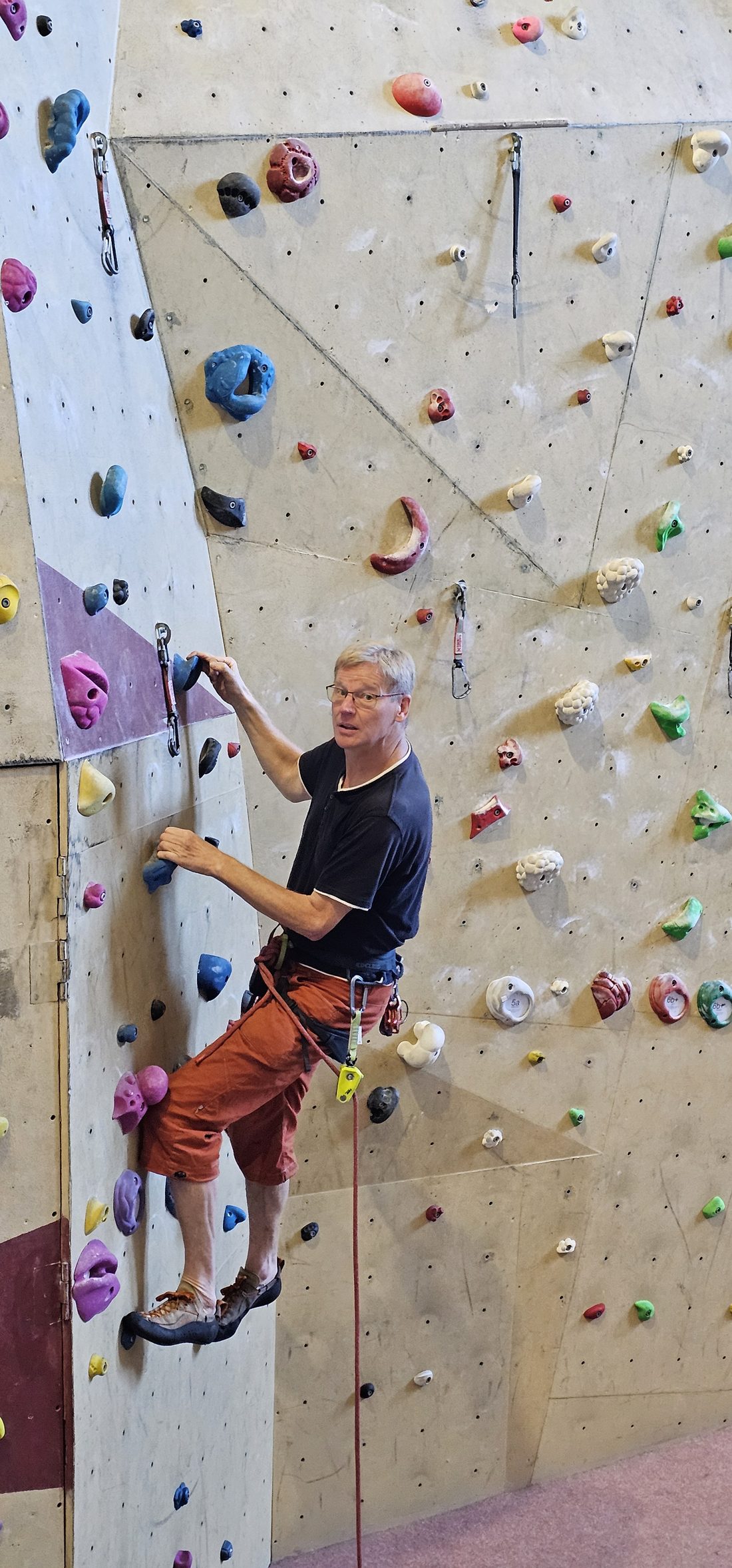 Kletterer an einer Indoor-Kletterwand – Ausgangspunkt für den Weg an den Fels